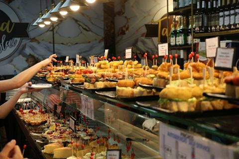 Barra de bar con pintxos y clientes eligiendo